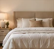 Restful neutral bedroom with ivory bedding and a taupe headboard